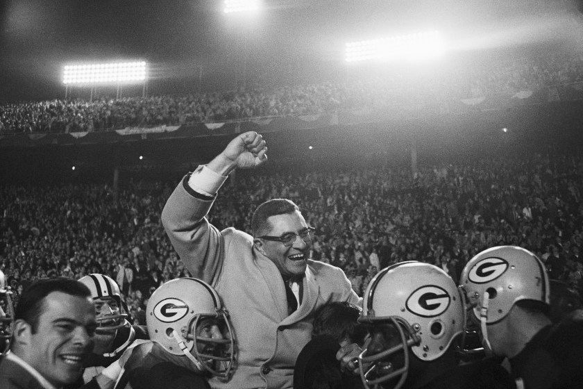 Vince Lombardi is hoisted up by players.