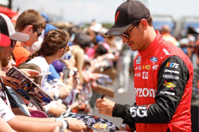 NASCAR driver Joey Logano signs autographs with fans. 