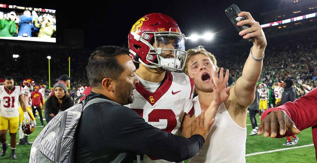 SOUTH BEND, INDIANA - OCTOBER 14: A fan takes a selfie with Caleb Williams #13 of the USC Trojans after the Notre Dame Fighting Irish defeated the USC Trojans and rushed the field at Notre Dame Stadium on October 14, 2023 in South Bend, Indiana.