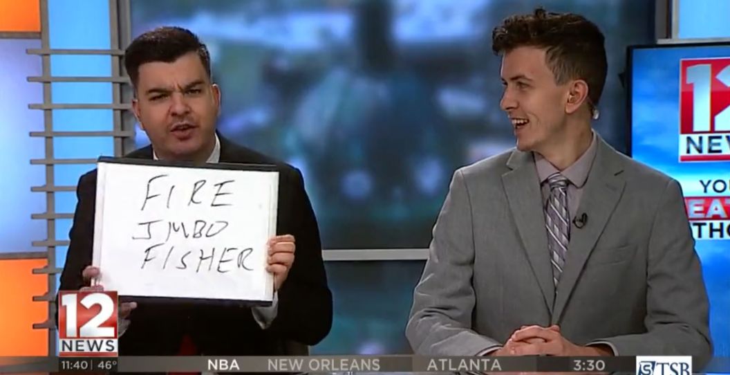 A news anchor holds up a "Fire Jimbo Fisher" sign.