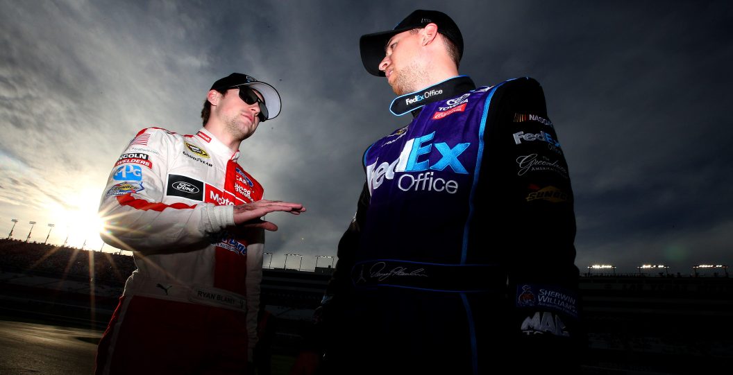 LAS VEGAS, NV - MARCH 04: Ryan Blaney, driver of the #21 Motorcraft / Quick Lane Tire Auto Center Ford, talks with Denny Hamlin, driver of the #11 FedEx Office Toyota, during qualifying for the NASCAR Sprint Cup Series Kobalt 400 at Las Vegas Motor Speedway on March 4, 2016 in Las Vegas, Nevada.