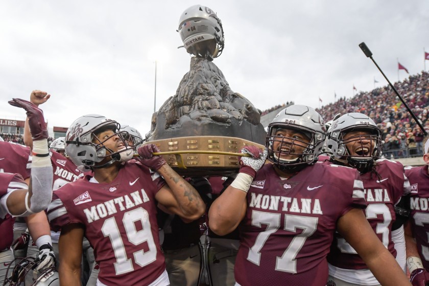 Montana players hold up a trophy after beating Montana State.