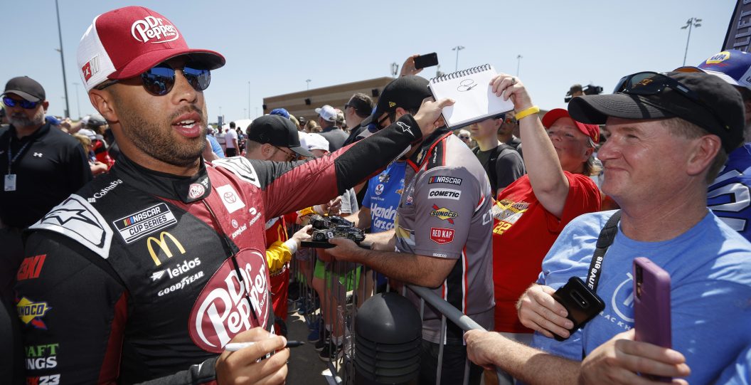 KANSAS CITY, KANSAS - MAY 07: Bubba Wallace, driver of the #23 Dr Pepper Zero Sugar Toyota, signs an autograph for a NASCAR fan on the red carpet prior to the NASCAR Cup Series Advent Health 400 at Kansas Speedway on May 07, 2023 in Kansas City, Kansas.