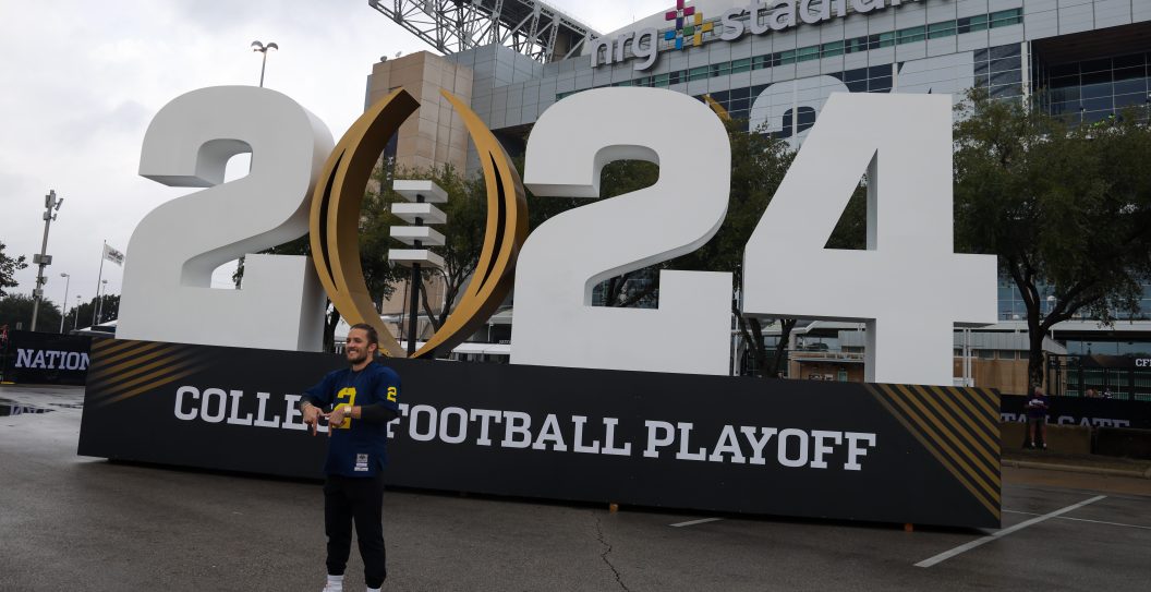 HOUSTON, TX - JANUARY 08: a Michigan fan takes a photo in front of the 2024 CFB logo before the College Football Playoffs National Championship game Michigan Wolverines and Washington Huskies on January 8, 2024, at NRG Stadium in Houston, Texas.