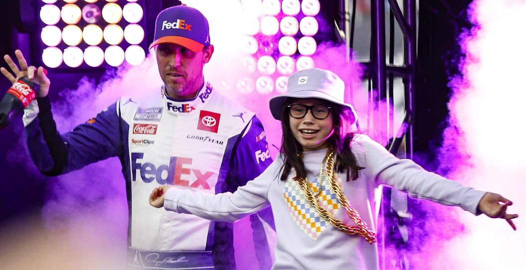 BRISTOL, TENNESSEE - SEPTEMBER 17: Denny Hamlin, driver of the #11 FedEx Ground Toyota, waves to fans as he walks onstage with his daughter, daughter, Taylor during driver intros prior to the NASCAR Cup Series Bass Pro Shops Night Race at Bristol Motor Speedway on September 17, 2022 in Bristol, Tennessee.