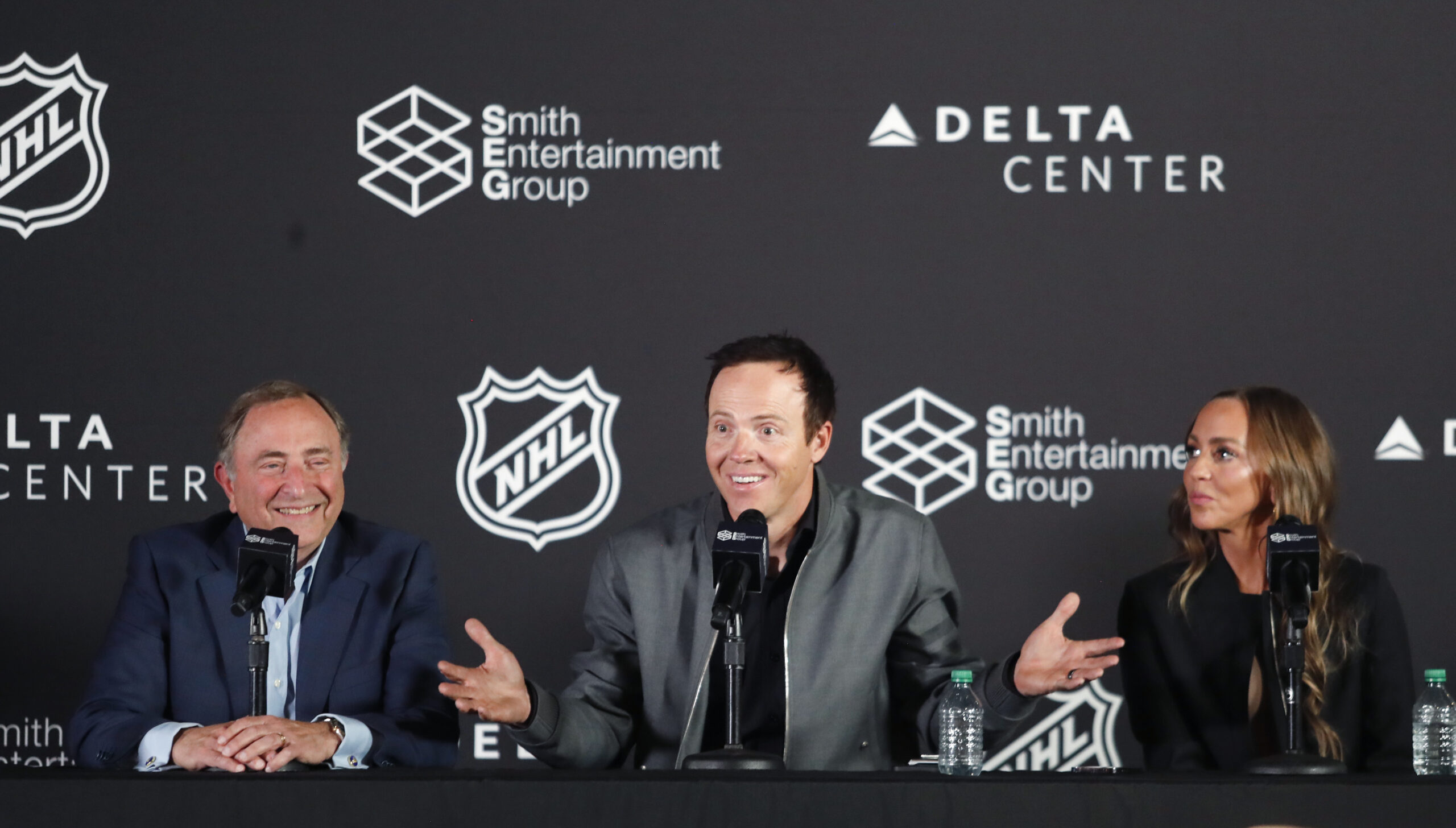 NHL Commissioner Gary Bettman and Ashley Smith smile as team owner Ryan Smith gestures during a news conference. The NHL has allowed the sale of the Arizona Coyotes and the team will relocate to Salt Lake City, Utah. (Getty)